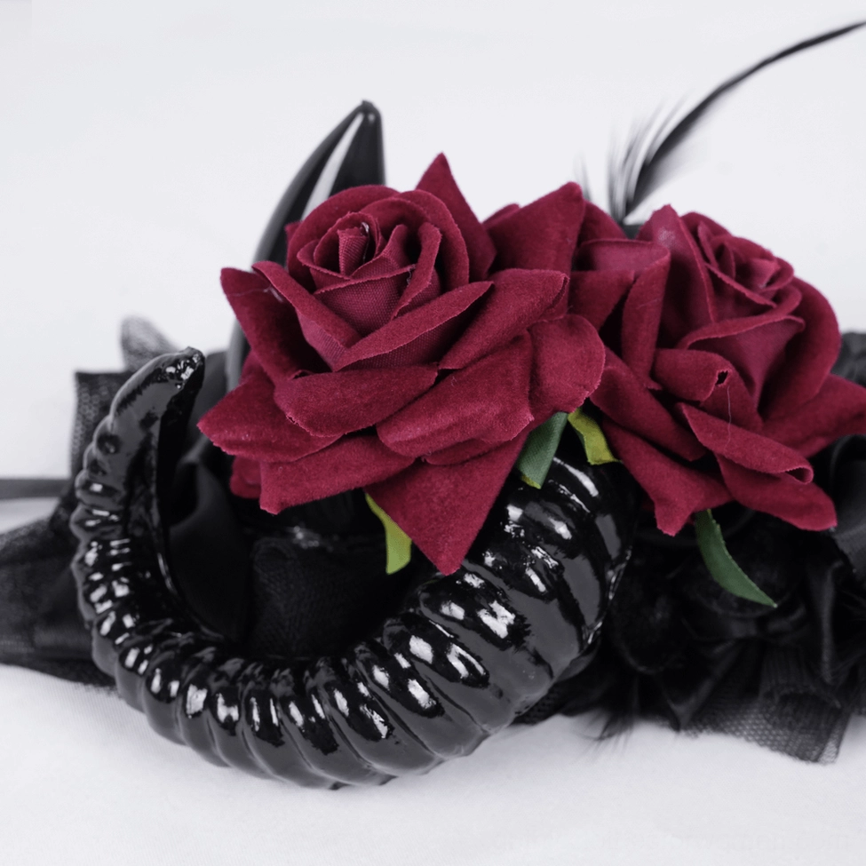 Close-up macro view of gothic headpiece focal details showing hand-arranged velvet red roses and polished black ram horns with refined craftsmanship