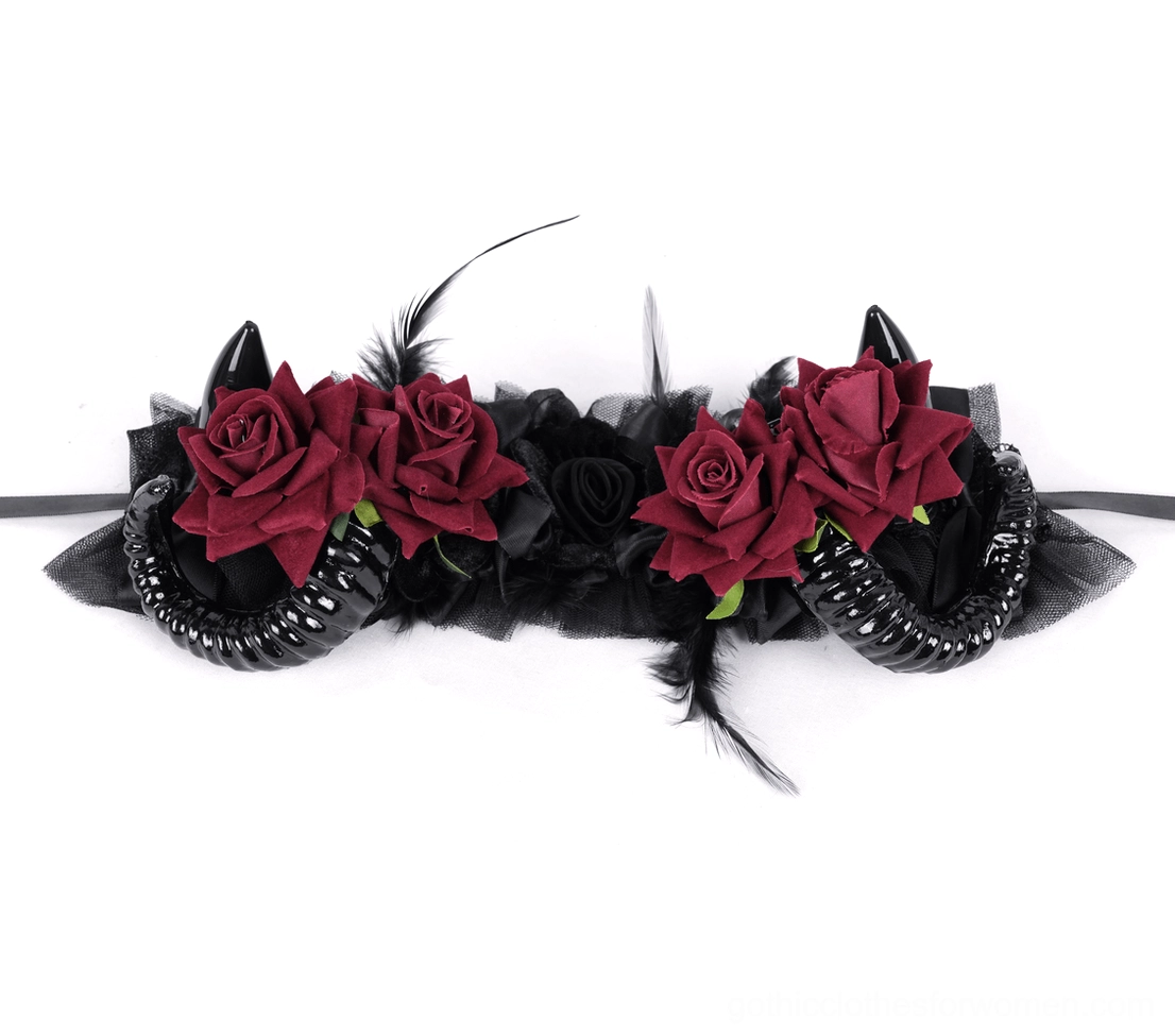 Flat lay overhead top-down view of complete gothic horned headpiece showing red velvet roses, black spiral horns, feather trims, and long black ribbon ties