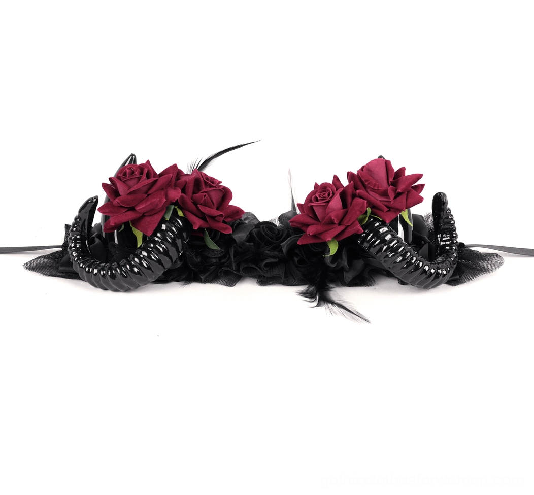 Side flat lay view of gothic ram horn headpiece displaying clustered red roses, polished black spiral horns, and feather accent details