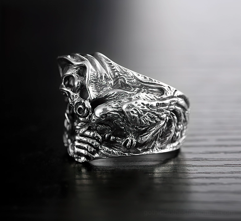 Gothic skull ring with carved bird detail and skeletal hand, vintage sterling silver finish on dark backdrop