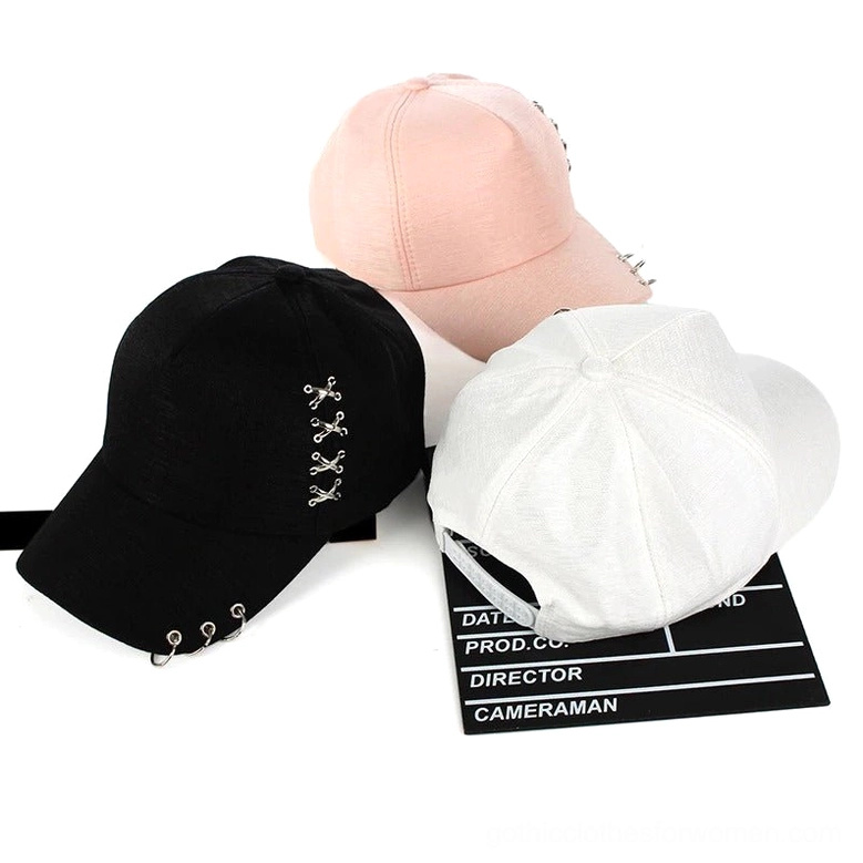 Top-down flat lay of multiple gothic ring baseball caps in black white and pink with metal ring detail