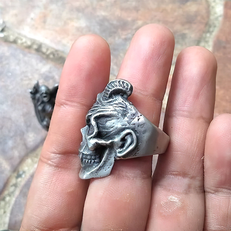 Rear side profile view of gothic demon skull ring on hand with polished silver finish against stone background