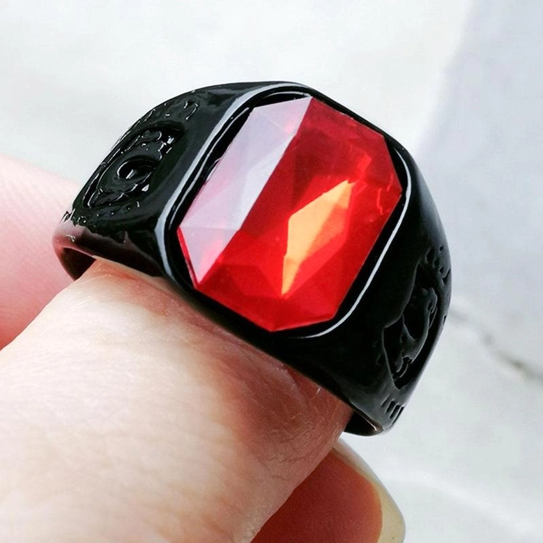 Black gothic signet ring with red glass stone worn on human finger close-up showing high-polished finish
