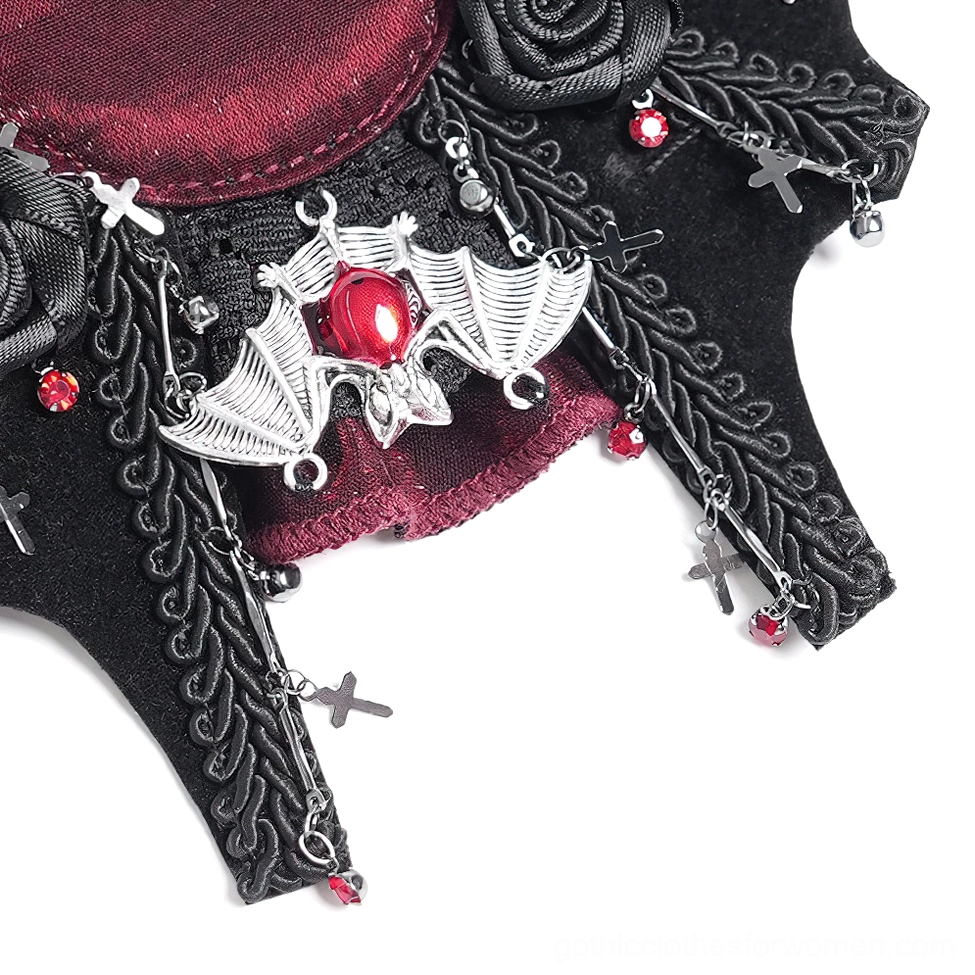 Angled close-up view of gothic hair clip showing silver bat charm accents, dangling cross chains, and red gem embellishments