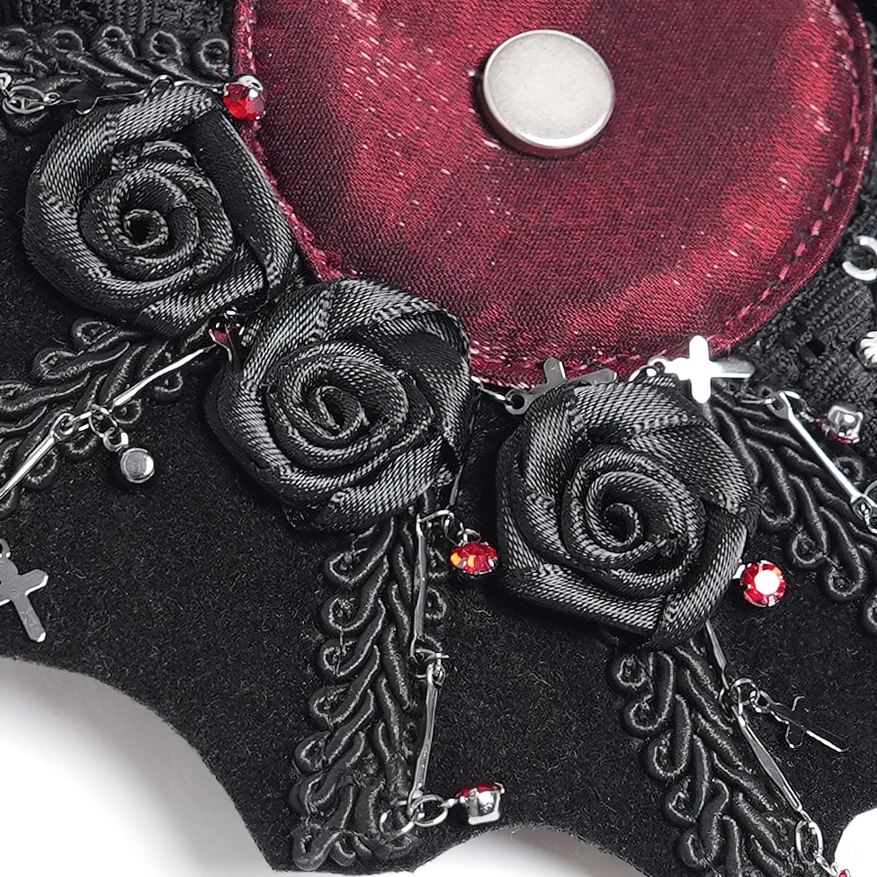 Top close-up detail of black gothic hair clip featuring burgundy satin roses, red rhinestones, and ornate silver cross charm