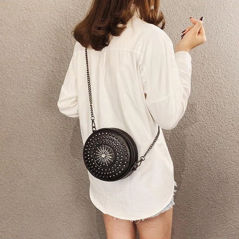 Woman wearing black gothic round crossbody bag back view with metal chain strap over shoulder