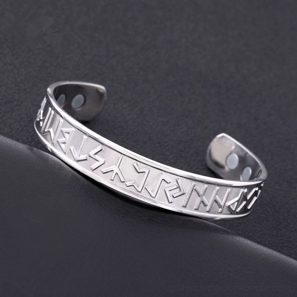 Polished silver stainless steel rune bracelet with magnetic dots topdown dark leather background