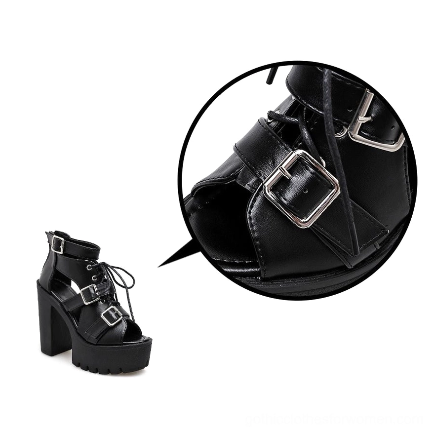 Close-up detail of black platform sandal showing buckle hardware and intricate lace-up front design