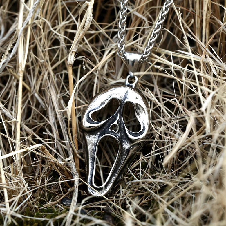 Side oblique view of screaming face gothic pendant necklace, slim stainless steel design with twisted chain