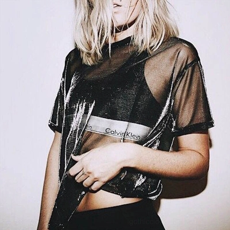 Sheer mesh gothic t-shirt styled with iridescent silver-black finish, paired with layered bralette, casual indoor setting