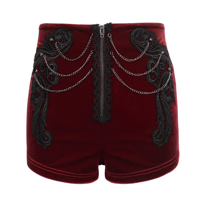 Front flat lay detail of wine red velvet shorts with black lace, metal chains, and red gem accents