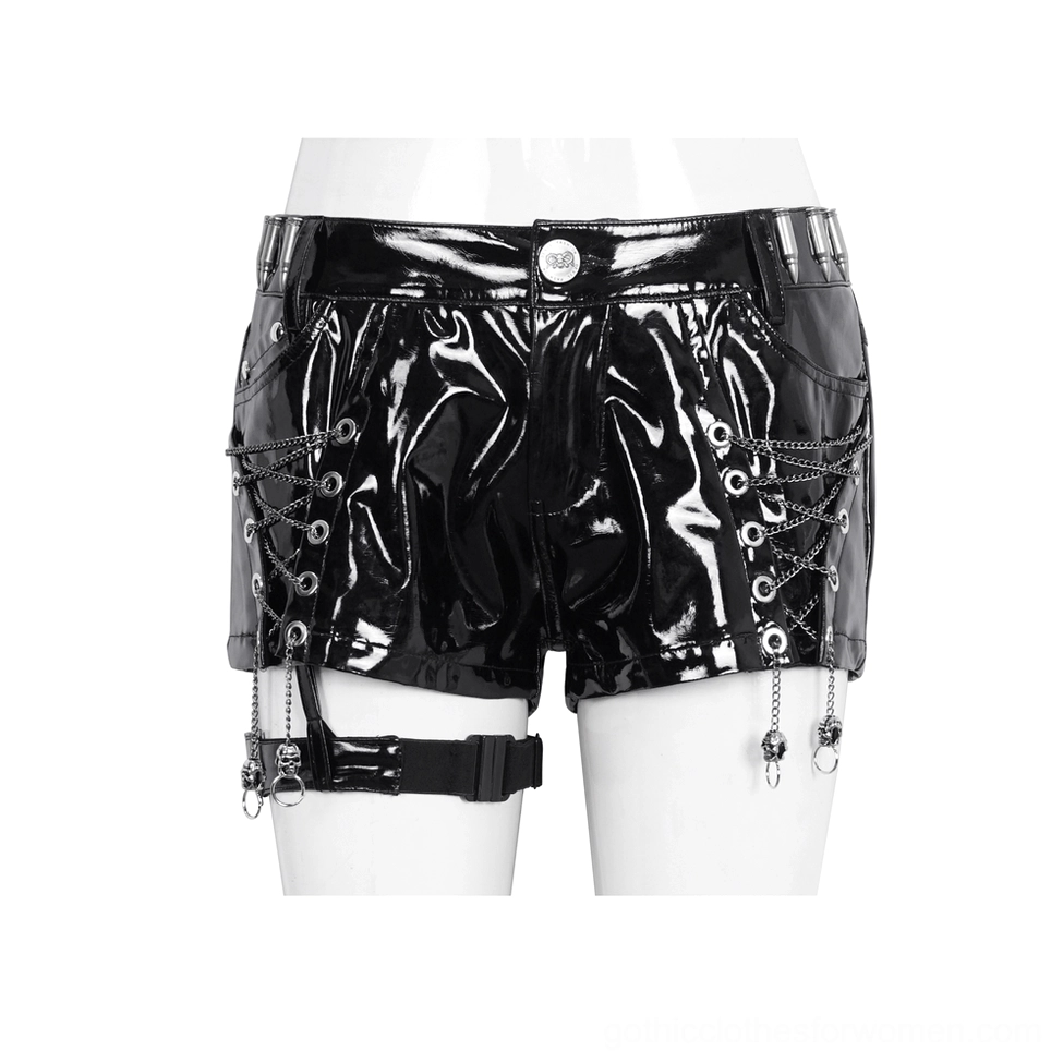 Mannequin wearing glossy black patent leather shorts with drop-chain pendants, side lace-up grommets and metal waist button
