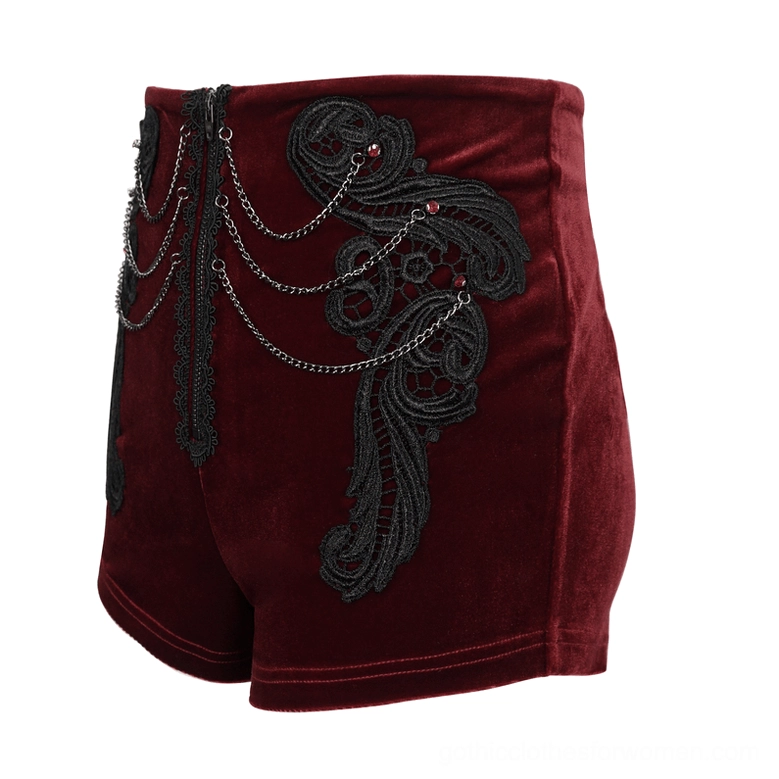 Side view flat lay of wine red gothic shorts showing black lace appliqué and multi-layer metal chain decorations