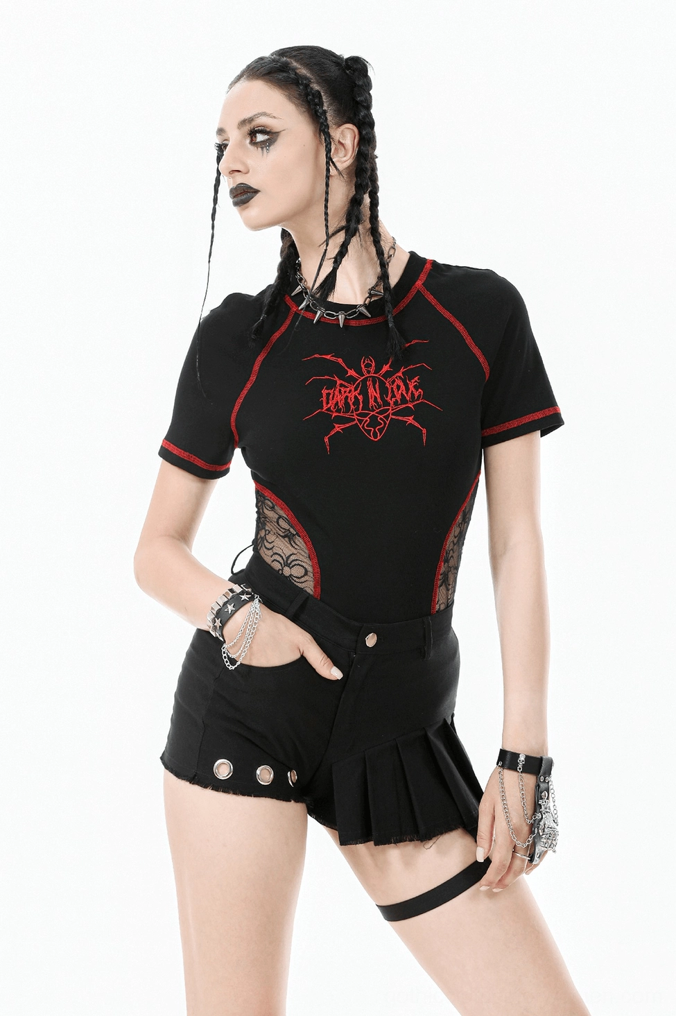 Model wearing black asymmetrical gothic pleated shorts with O-ring strap in studio setting