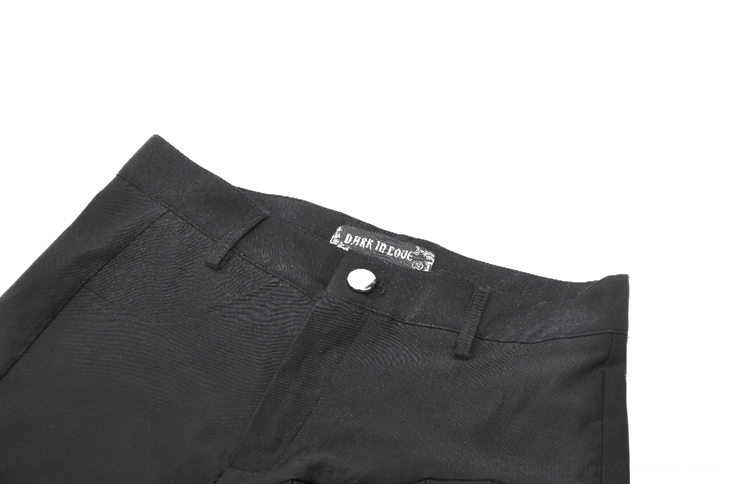Close-up detail of gothic shorts waistband, metal button closure, and brand woven label