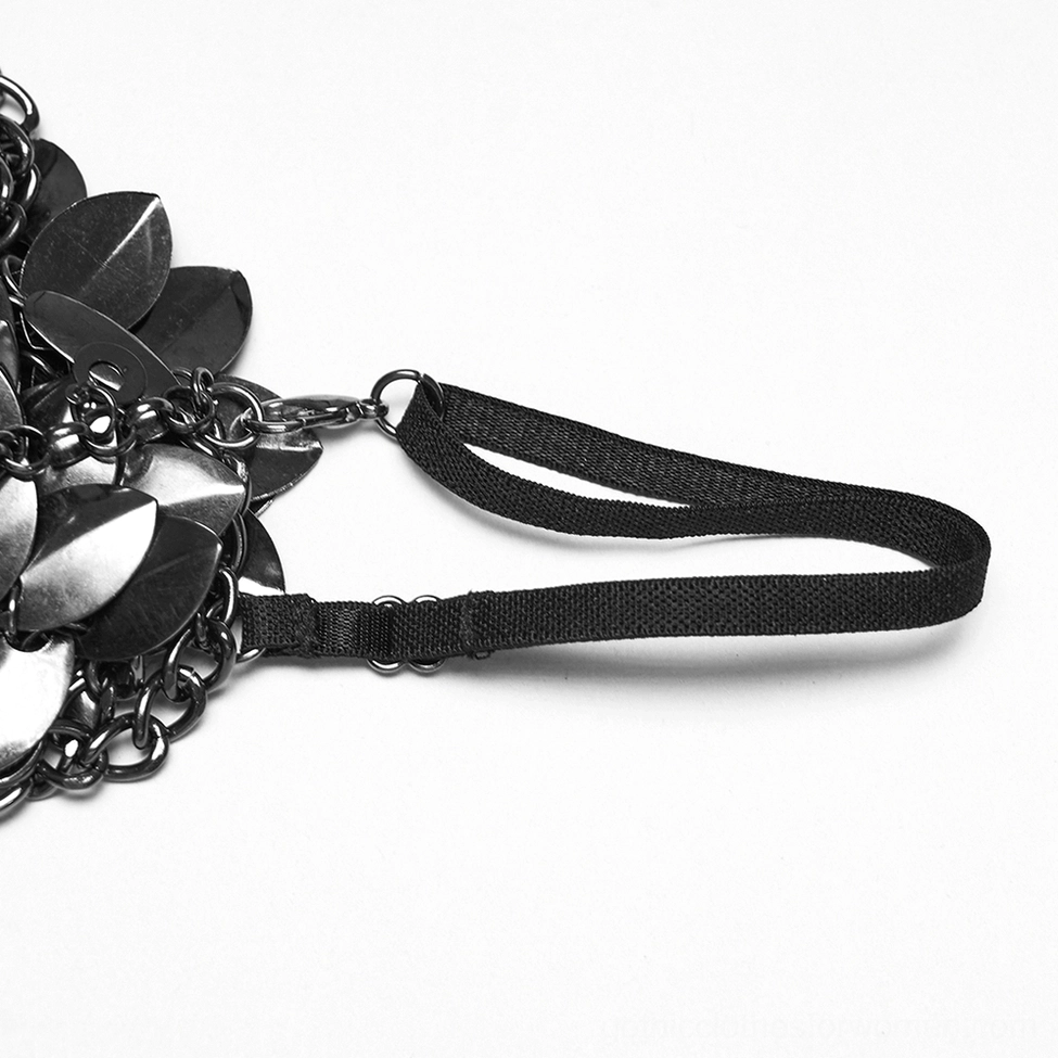 Close-up flat lay of gothic shoulder armor scale pieces with adjustable fabric straps and metal chain components