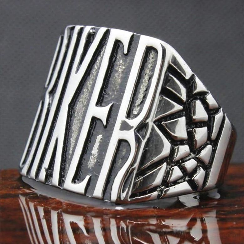 Biker ring angled view on wood showing textured side ornament and distressed silver patina