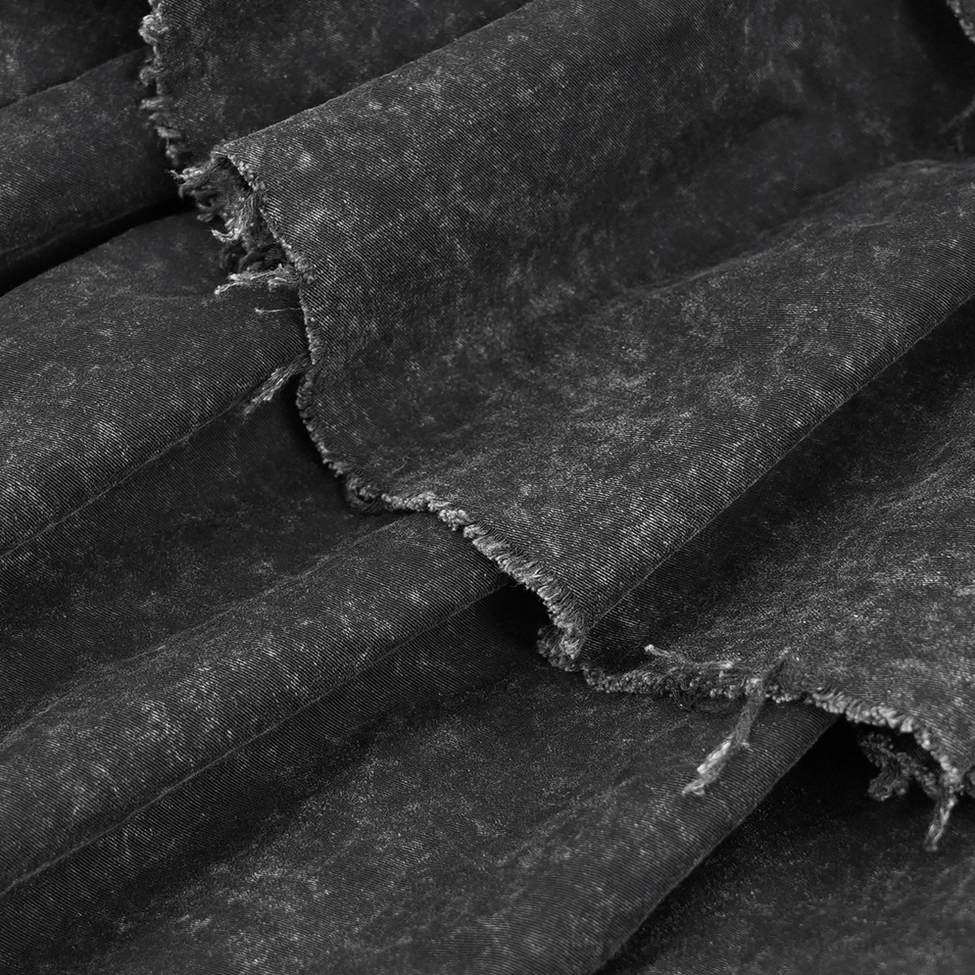 Detailed view of black gothic skirt showing raw frayed hem edges on tiered layers and washed fabric texture