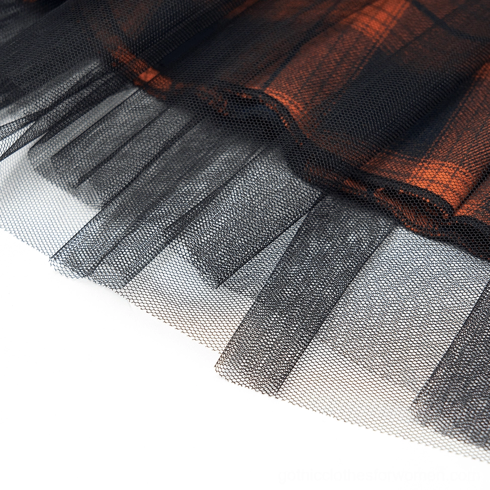 Close-up detail of black and orange plaid gothic mesh skirt hem showing combined tulle mesh and plaid fabric layering technique