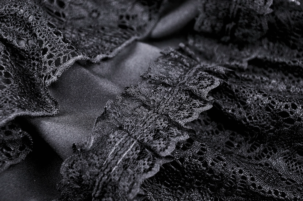 Close-up of black gothic skirt ruffled lace edge trim with satin fabric underlayer showing texture