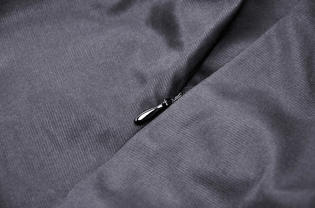 Flat close-up detail of hidden side zipper on black gothic A-line skirt showing woven fabric texture