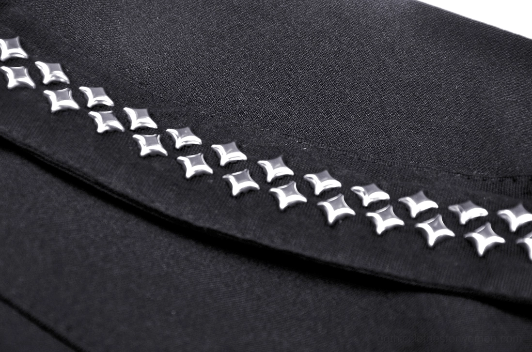 Detailed close-up of gothic skirt fabric trim with star-shaped metal studs on black woven material