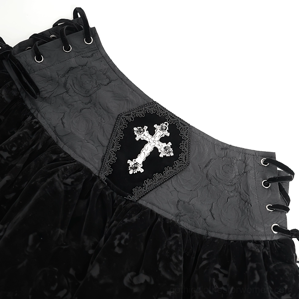 Close-up detail of black gothic skirt waist side showing silver cross embellishment, embossed velvet waistband, and corset lace-up holes