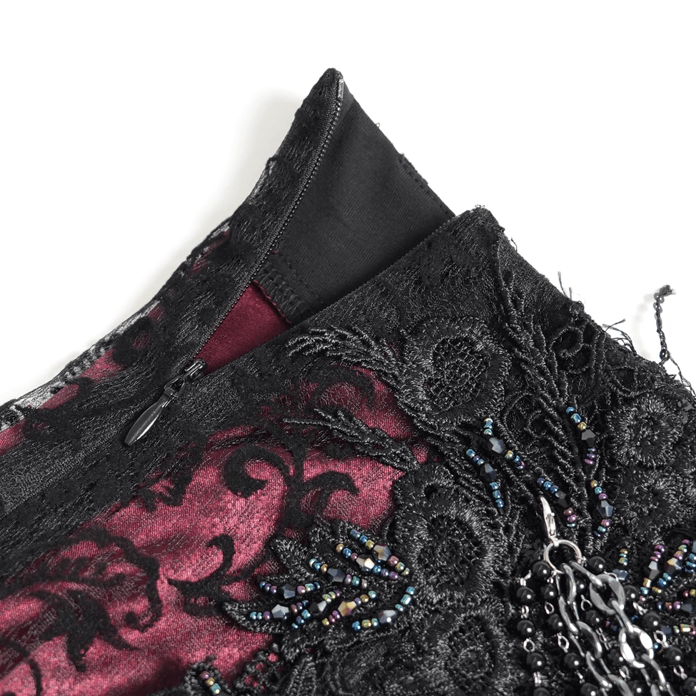 Top-down close-up of skirt waistband showing hidden zipper closure, beaded floral trim and metal chain accents