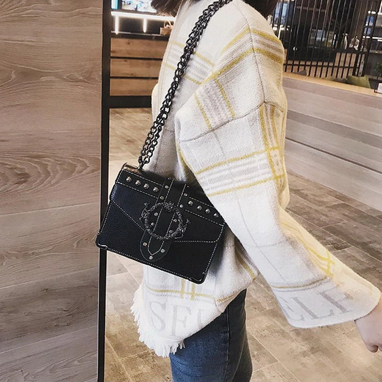 Woman wearing black gothic skull rivet chain shoulder bag with plaid coat - styled outfit inspiration