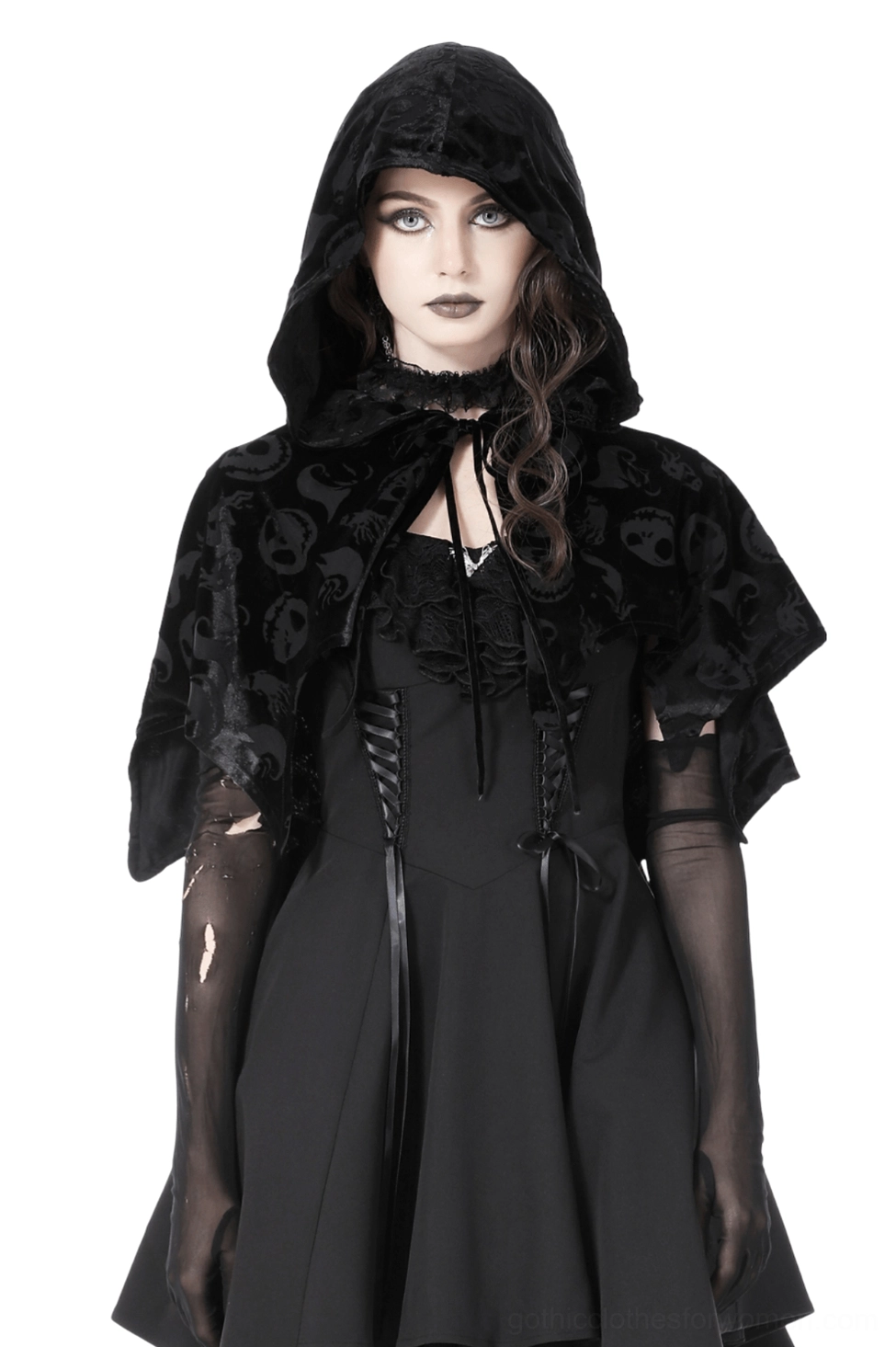 Black velvet gothic hooded cape with embossed skull print, front view on model showcasing draped silhouette and bat-wing hem design