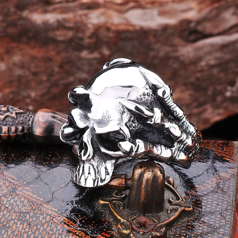 Gothic skull claw ring - rock style stainless steel biker jewelry, side oblique view on vintage background