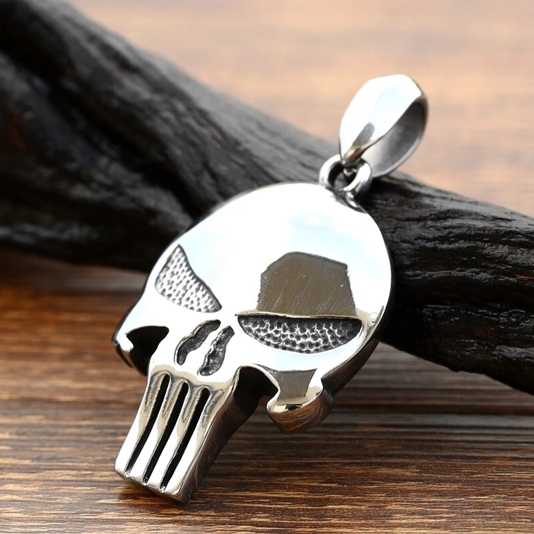 Dark gothic skull pendant displayed on wooden surface with atmospheric props, showing realistic scale and polished metal finish