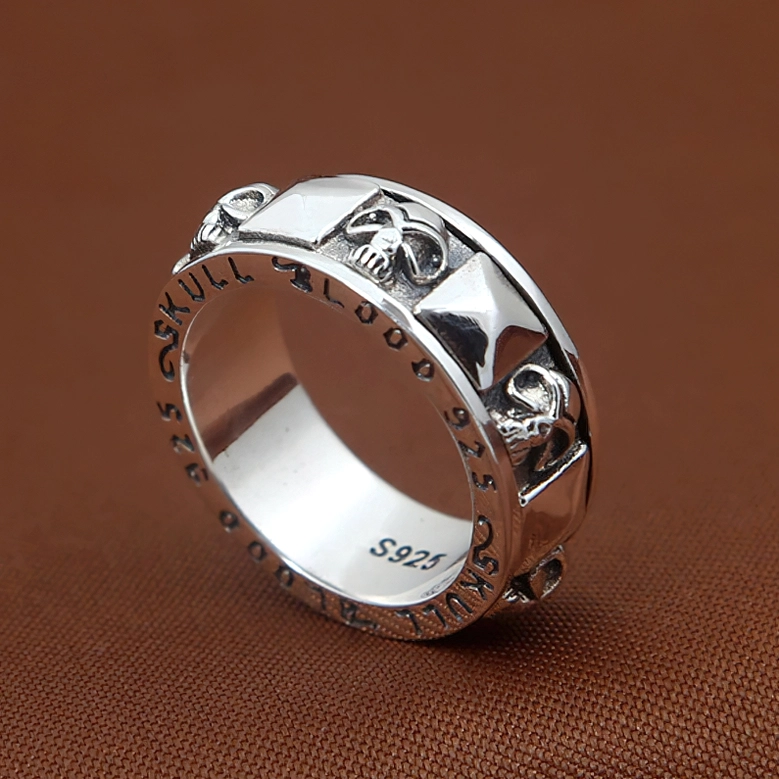 Three-quarter side view of gothic skull and pyramid spinner ring showing S925 mark and complete design