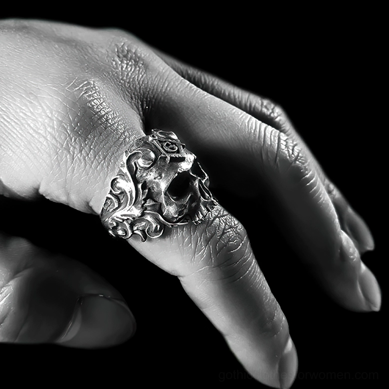 Close-up side view of Masonic skull ring on index finger showing textured skull details and floral vine engravings