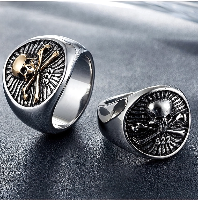 Matching pair of gothic skull signet rings in mixed gold and silver on dark leather, styled flat lay