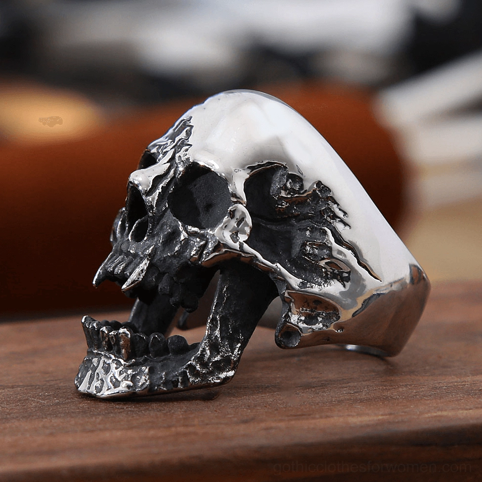 Stainless steel gothic skull ring left side profile on wooden surface, polished smooth with distressed black details