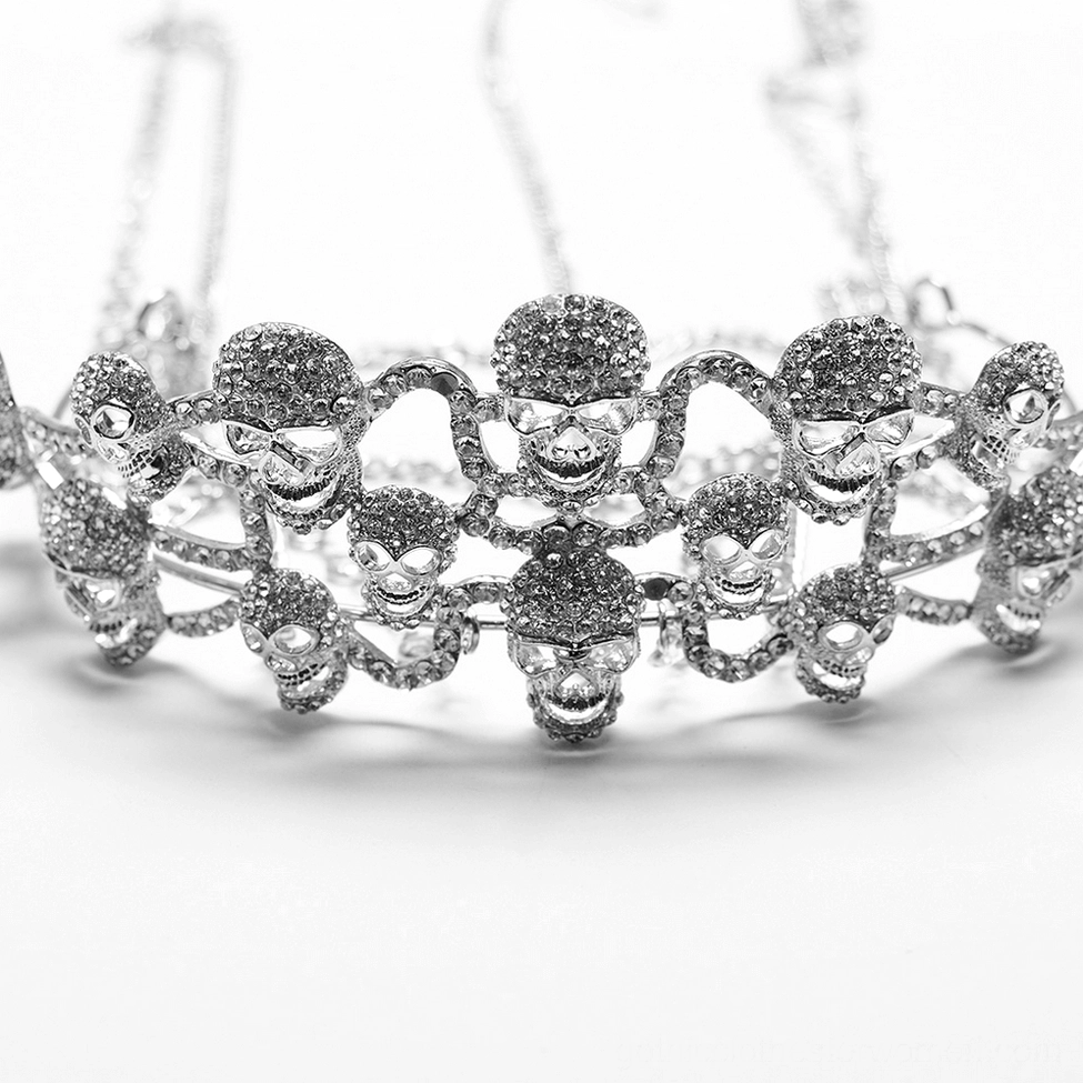 Top-down close-up detail shot of skull-shaped metal embellishments and gem-encrusted silver crown design