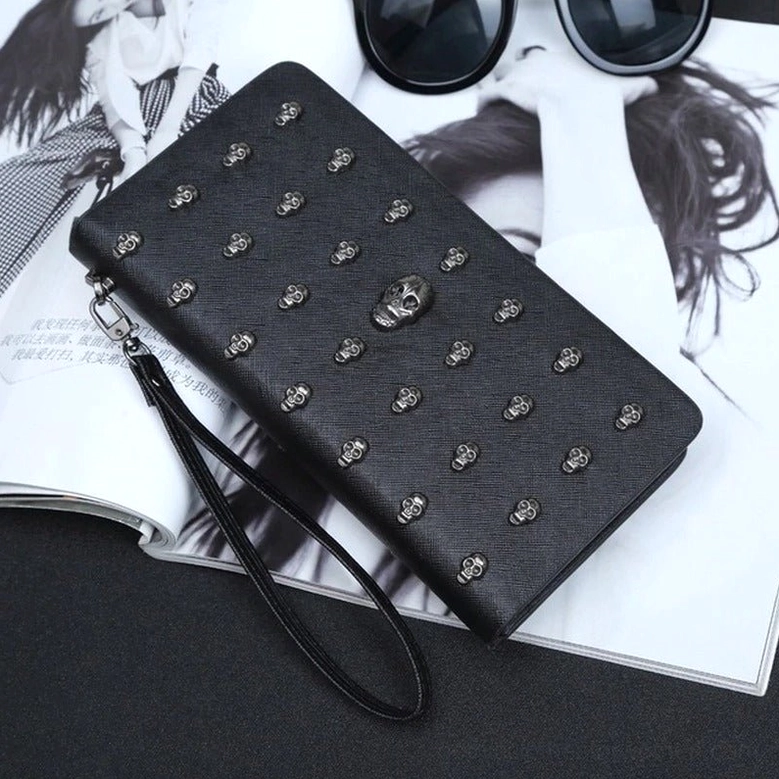 Black gothic skull wallet styled on fashion magazine desktop with sunglasses, featuring silver skull decorations and wrist strap, lifestyle photography