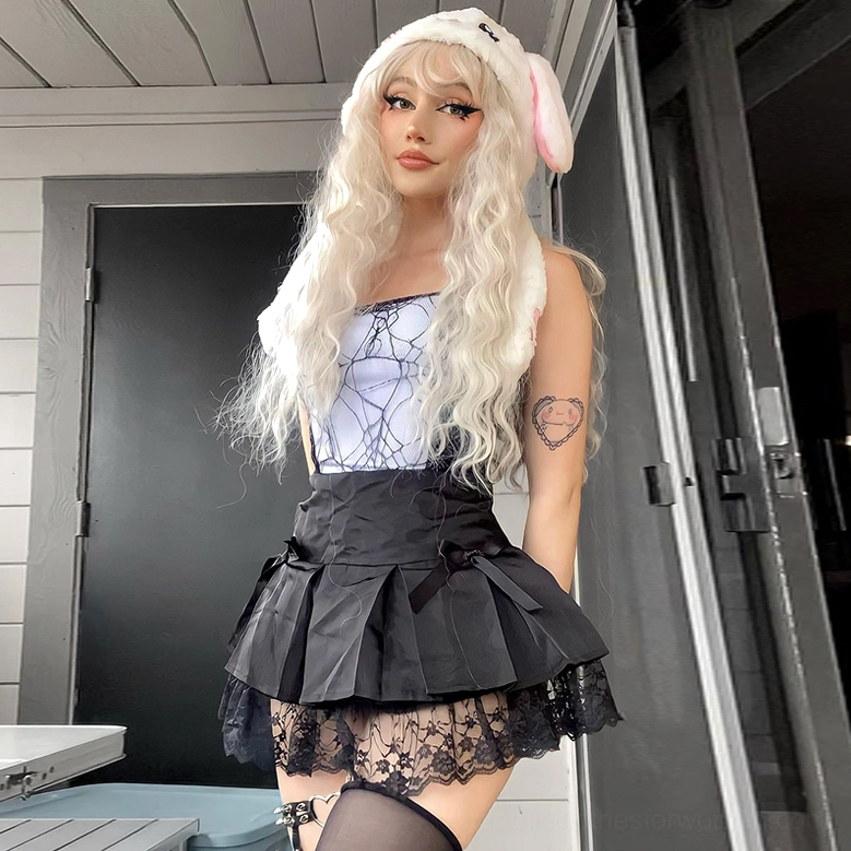 White and black gothic spider web crop top worn with pleated skirt, three-quarter view, complete gothic outfit coordination