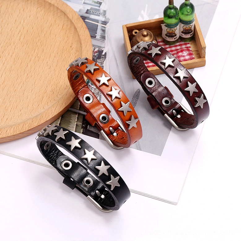 Three gothic star leather bracelets in black brown and camel displayed together in top-down flat lay with lifestyle props