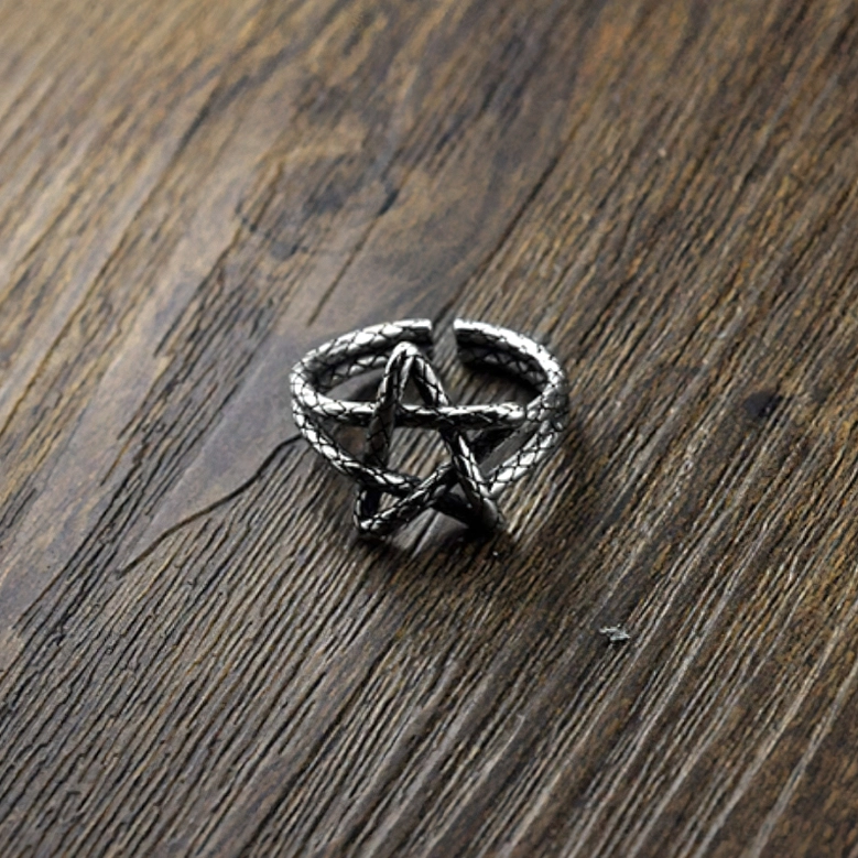 Top view of aged silver pentagram ring on wood surface highlighting hollow star geometry and adjustable opening