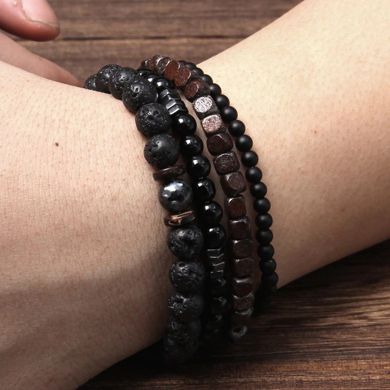 Beaded bracelet set stacked on real human wrist close-up showing natural stone and wooden beads with gothic dark aesthetic worn styling