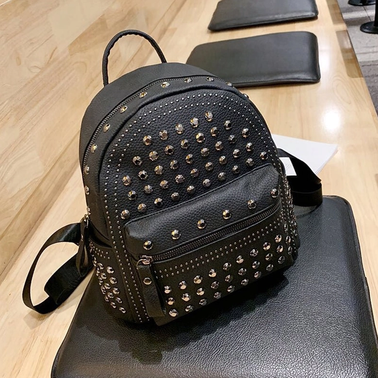 Black gothic rivet backpack flat lay showing multiple zipper pockets and metal rivet accent details