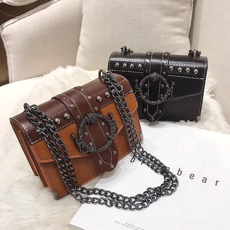 Brown and black gothic studded crossbody bags displayed on fluffy cushion - side angle view showing depth and structure