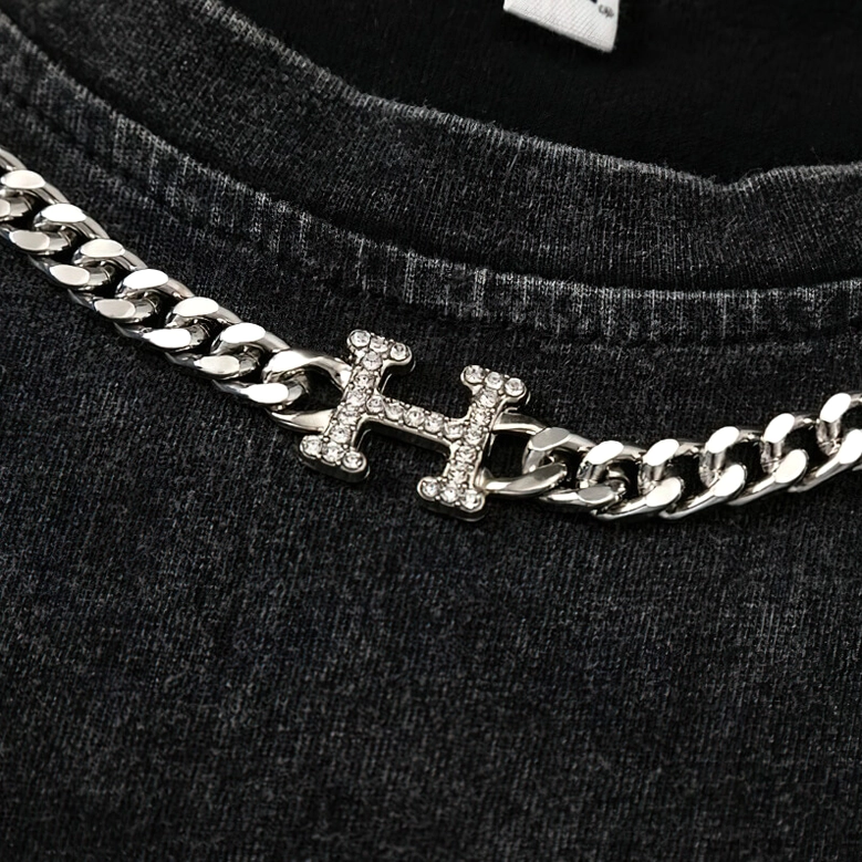 Macro close-up of silver curb chain with inlaid rhinestones attached to gothic tank top crew neck