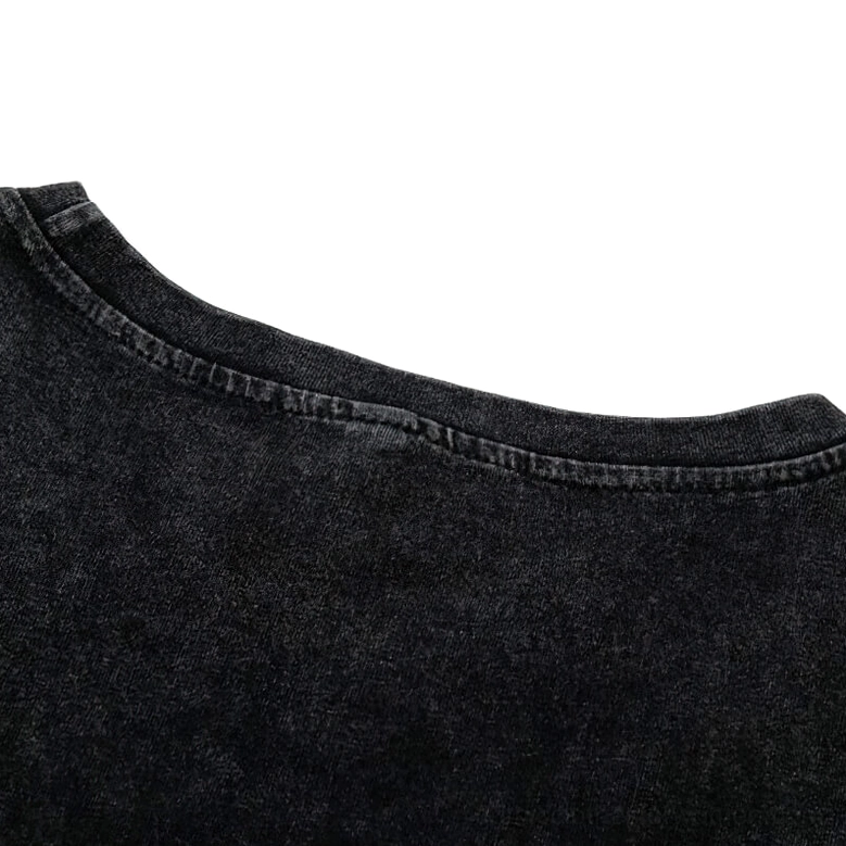 Distressed frayed ripped bottom hem of black faded cotton gothic tank top showing intentional wear design