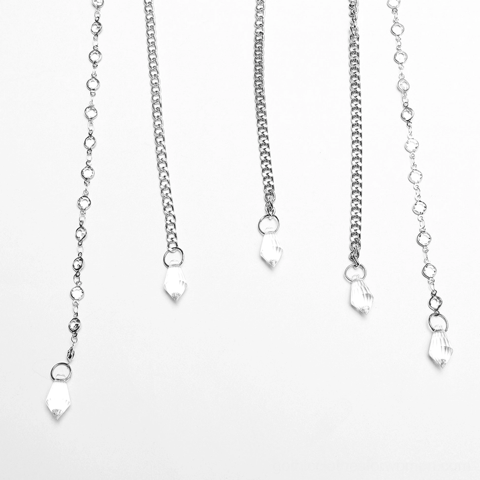 Flat lay shot of gothic tiara chain components featuring silver chains with crystal drop pendants on white background