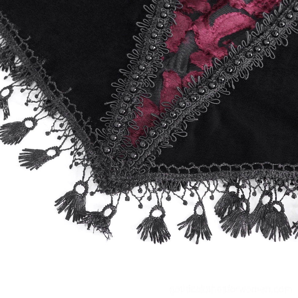 Close-up of tassel fringe trim and lace edging on embroidered velvet hem of gothic top