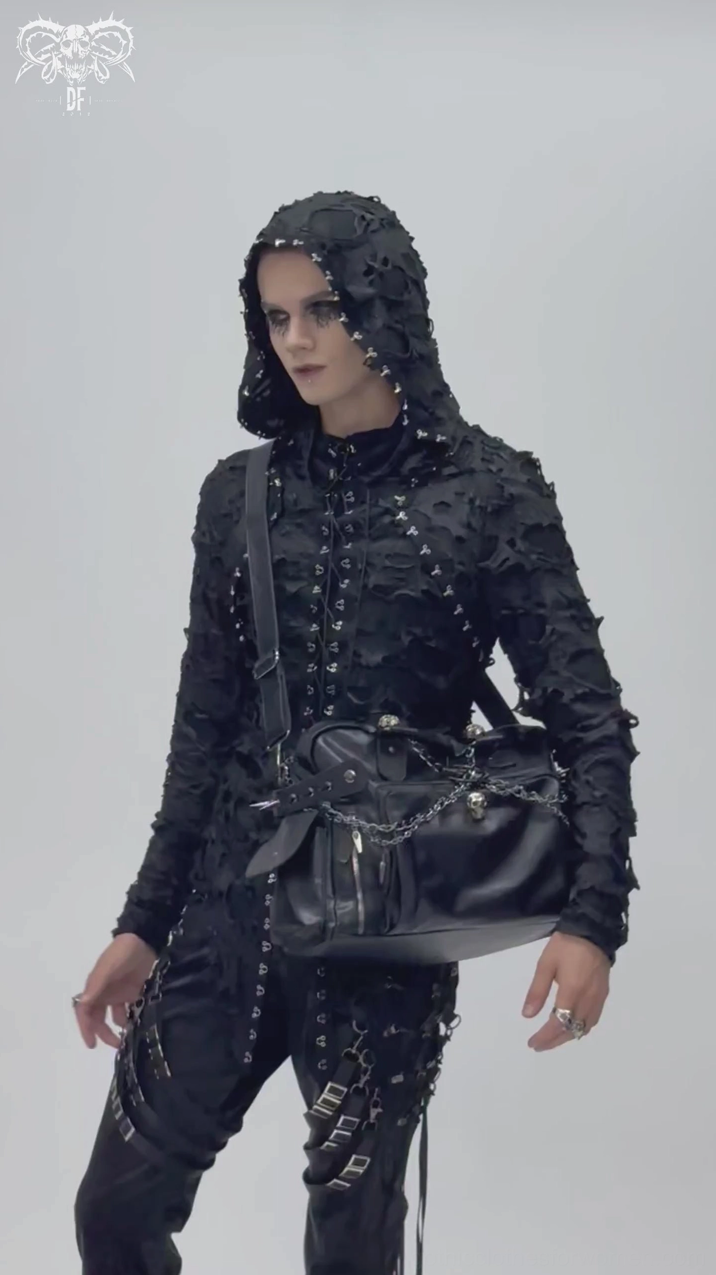Model wearing black gothic tote bag in three-quarter front view, showing crossbody carry style with hooded goth outfit