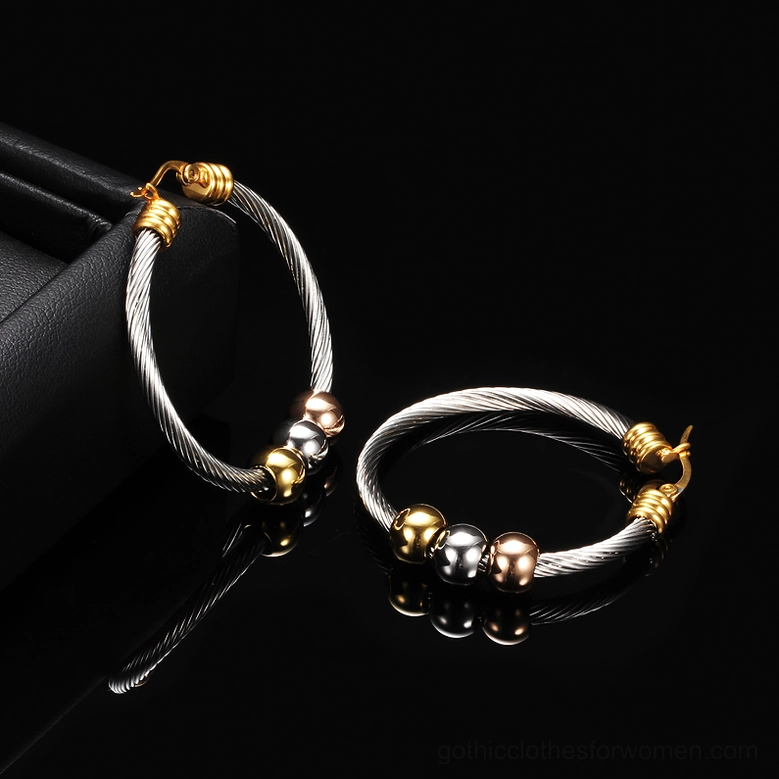 Two sizes of twisted gothic hoop earrings with tri-color metal beads on black jewelry tray showcasing design variation
